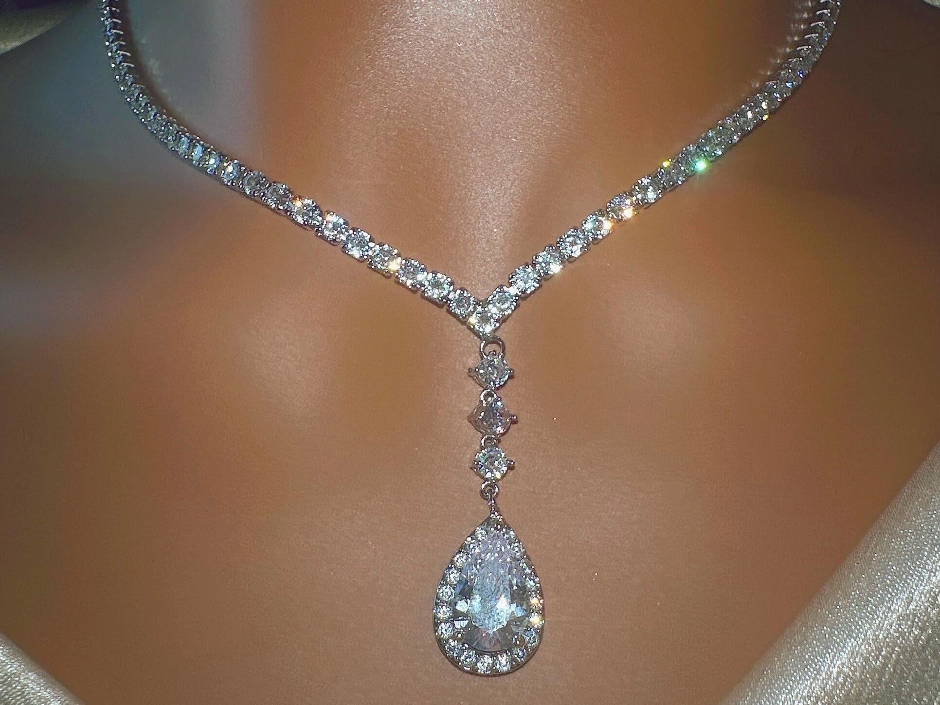 Close-up of elegant dainty diamond sparkly teardrop silver pendant and necklace on a neckline.