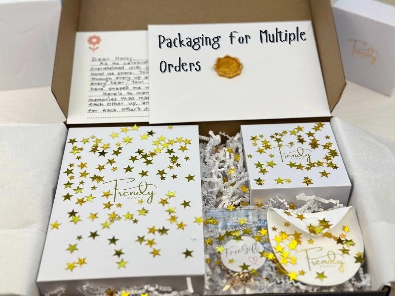 Packaging of multiple jewelry order in trendyadore white and gold jewelry box. The jewelry boxes are arranged in a bigger box with crinkle cut papers and star sprinkles to beautify the product for the buyer or gift recipient. It also includes handwritten personalized message in a wax sealed enveope.