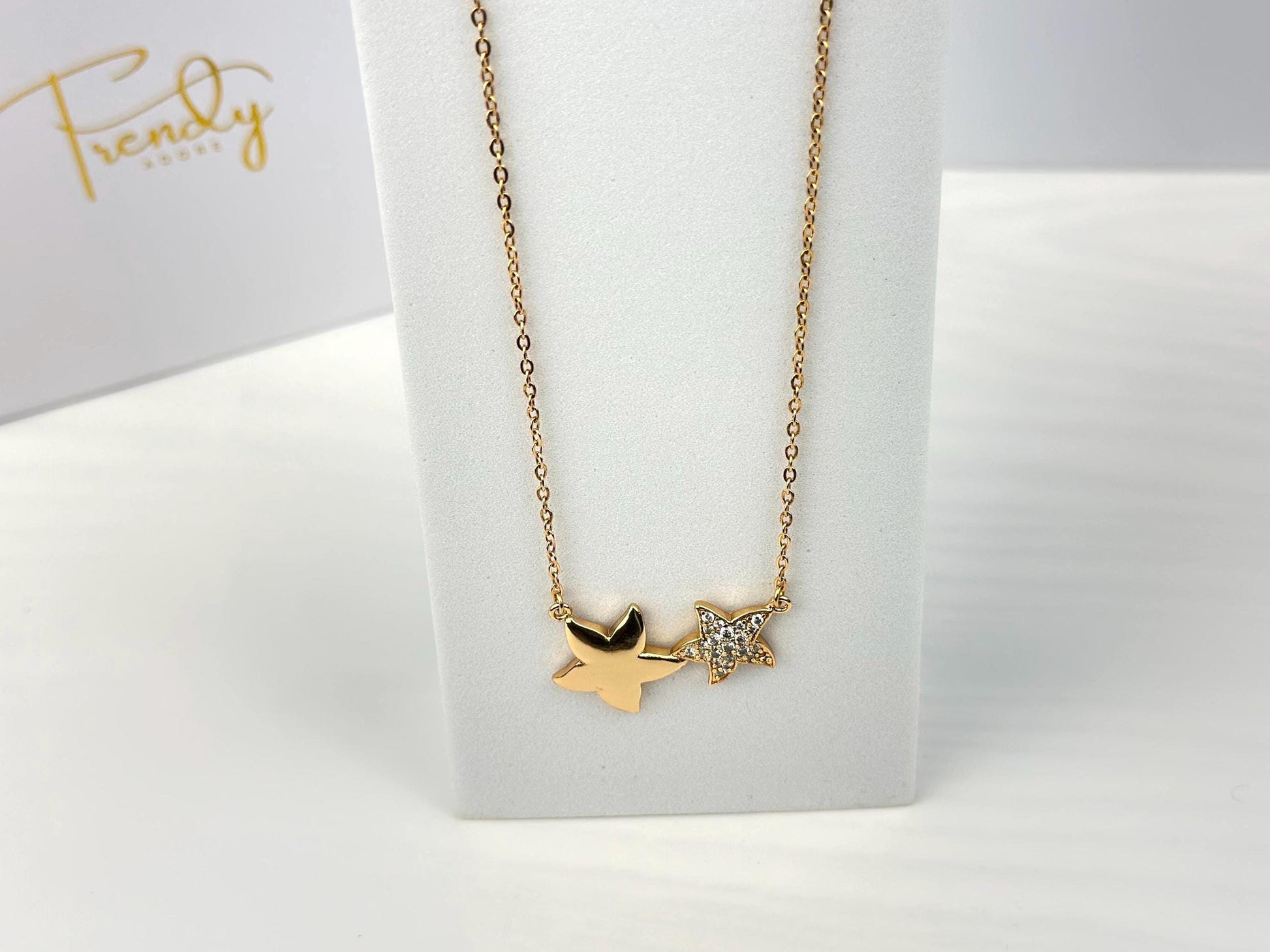 18K gold filled necklace with double star pendant. The stars are of different sizes sitting side by side. The necklace hung on a white prop to emphasize the beauty of the necklace